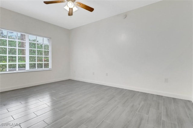 spare room with light wood finished floors, baseboards, and a ceiling fan