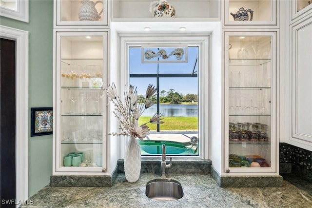3911 Lakemont Dr, Bonita Springs, FL 34134 - details featuring glass insert cabinets, a sink, and a water view