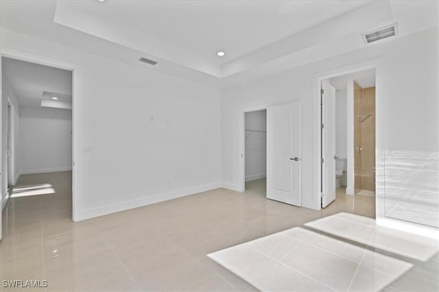 150 Bell Blvd S, Lehigh Acres, FL 33974 - unfurnished bedroom featuring a closet, visible vents, baseboards, a tray ceiling, and a walk in closet