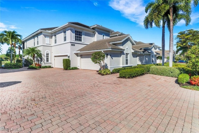 14561 Bellino Ter Unit 101, Bonita Springs, FL 34135 - view of front of home featuring a tiled roof, a garage, decorative driveway, and stucco siding