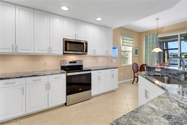 14561 Bellino Ter Unit 101, Bonita Springs, FL 34135 - kitchen featuring white cabinets, stainless steel appliances, dark stone countertops, a sink, and light tile patterned floors