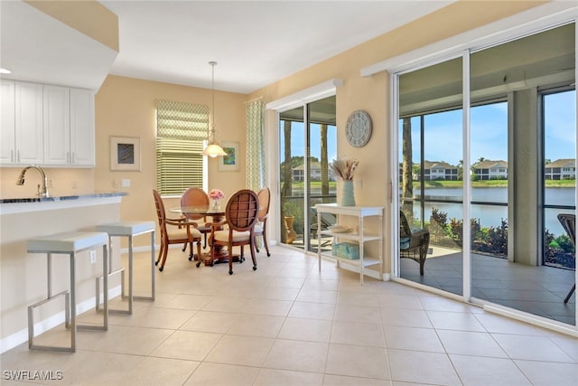 14561 Bellino Ter Unit 101, Bonita Springs, FL 34135 - dining space featuring baseboards, a water view, light tile patterned floors, and a healthy amount of sunlight