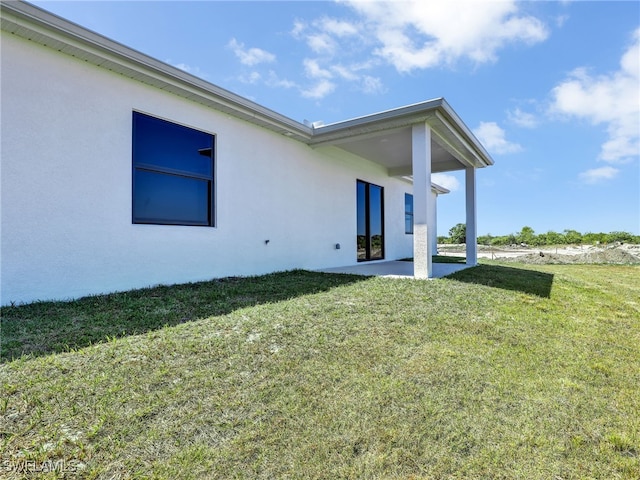 633 Cane St E, Lehigh Acres, FL 33974 - back of house with stucco siding, a patio area, and a yard