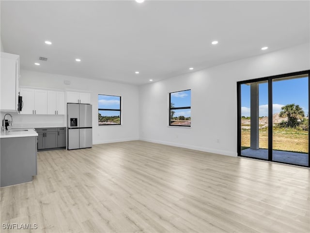 633 Cane St E, Lehigh Acres, FL 33974 - unfurnished living room featuring light wood-type flooring, recessed lighting, baseboards, and a sink
