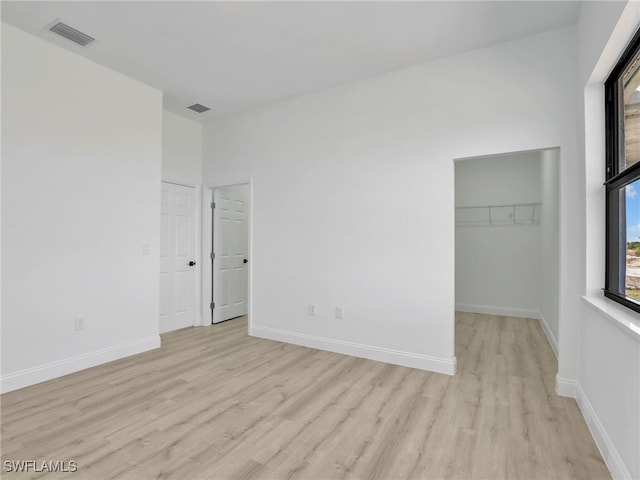 633 Cane St E, Lehigh Acres, FL 33974 - unfurnished bedroom with light wood-style flooring, a walk in closet, and baseboards