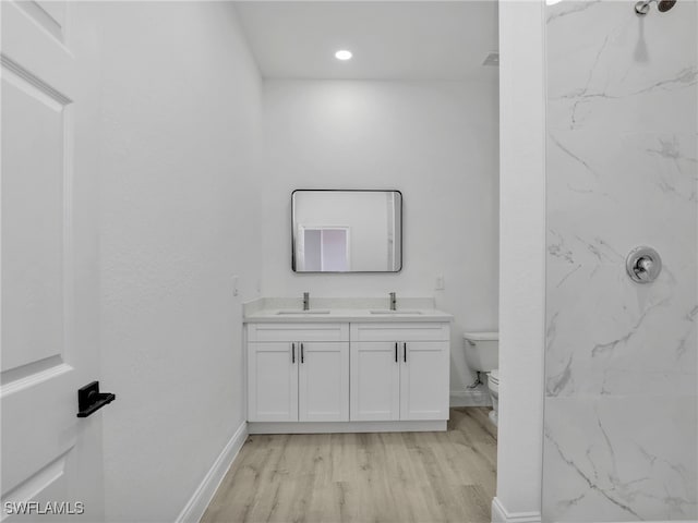 633 Cane St E, Lehigh Acres, FL 33974 - bathroom featuring toilet, double vanity, wood finished floors, baseboards, and a marble finish shower