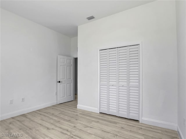 633 Cane St E, Lehigh Acres, FL 33974 - unfurnished bedroom with light wood finished floors, baseboards, and a closet