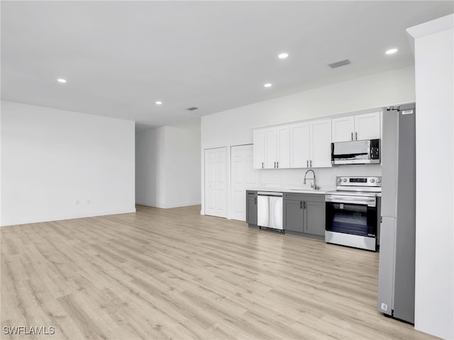 633 Cane St E, Lehigh Acres, FL 33974 - kitchen with appliances with stainless steel finishes, a sink, recessed lighting, light wood finished floors, and light countertops