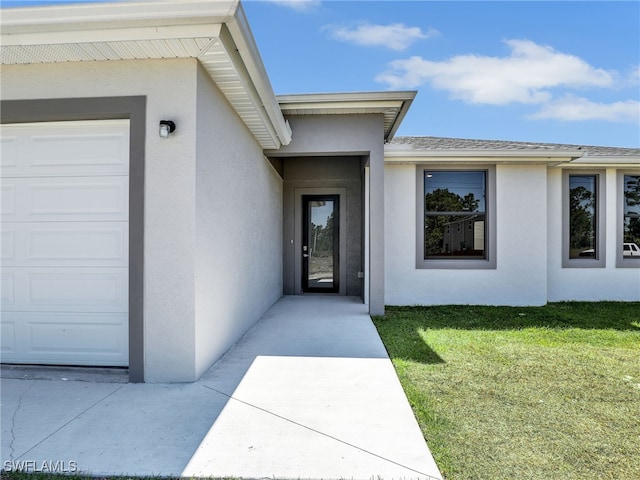 1134 Cumming St E, Lehigh Acres, FL 33974 - view of exterior entry with stucco siding, an attached garage, a lawn, and a shingled roof
