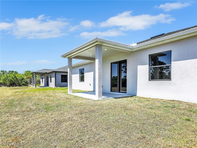 1134 Cumming St E, Lehigh Acres, FL 33974 - back of property featuring stucco siding, a patio area, and a lawn