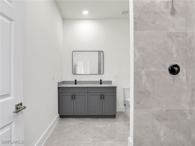 1134 Cumming St E, Lehigh Acres, FL 33974 - bathroom with double vanity, toilet, baseboards, tiled shower, and marble finish flooring