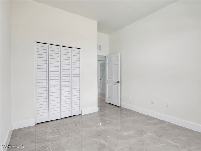 1134 Cumming St E, Lehigh Acres, FL 33974 - unfurnished bedroom with marble finish floors, baseboards, a high ceiling, and a closet