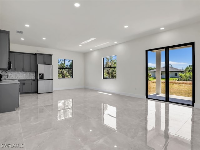 1134 Cumming St E, Lehigh Acres, FL 33974 - unfurnished living room featuring a sink, recessed lighting, light marble finish flooring, and baseboards