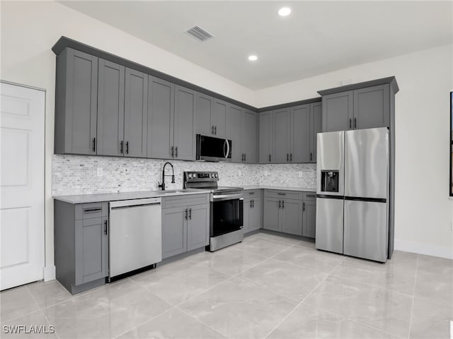 1134 Cumming St E, Lehigh Acres, FL 33974 - kitchen featuring stainless steel appliances, gray cabinetry, light countertops, a sink, and tasteful backsplash