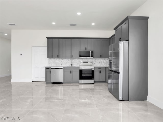 1134 Cumming St E, Lehigh Acres, FL 33974 - kitchen featuring stainless steel appliances, gray cabinets, a sink, tasteful backsplash, and recessed lighting