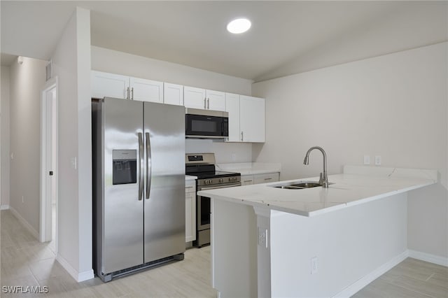 kitchen featuring a sink, a peninsula, white cabinets, light stone countertops, and appliances with stainless steel finishes