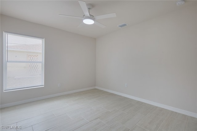 empty room featuring baseboards, visible vents, and a ceiling fan