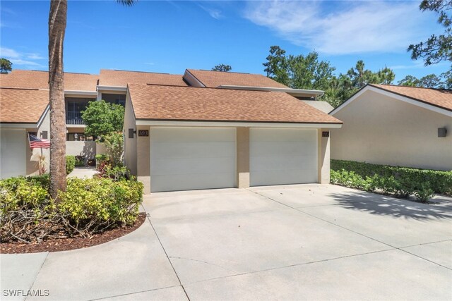 15450 Cedarwood Ln Unit 103, Naples, FL 34110 - view of front of house with a garage, a shingled roof, concrete driveway, and stucco siding