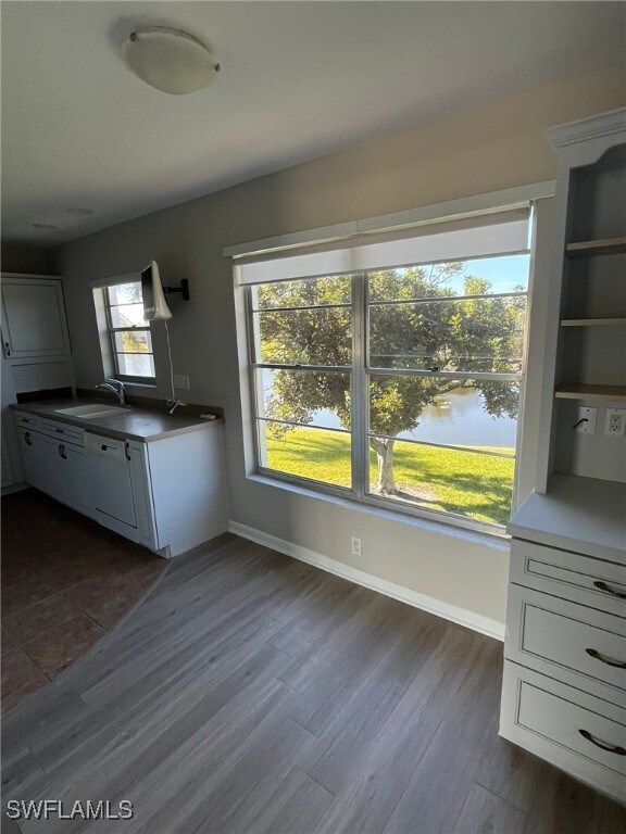 6824 Sandtrap Dr Unit 4, Fort Myers, FL 33919 - kitchen featuring a sink, open shelves, dark wood-style floors, baseboards, and white cabinets
