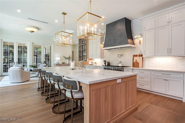 4300 Brynwood Dr, Naples, FL 34119 - kitchen with custom exhaust hood, tasteful backsplash, an inviting chandelier, light wood-type flooring, and light stone countertops