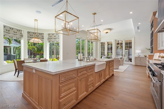 4300 Brynwood Dr, Naples, FL 34119 - kitchen with high end range, light wood-type flooring, an inviting chandelier, light stone countertops, and a sink