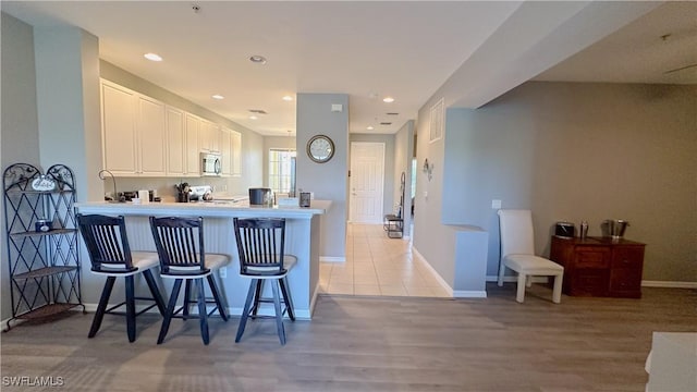 14512 Abaco Lakes Dr Unit 103, Fort Myers, FL 33908 - kitchen featuring white cabinetry, a kitchen bar, recessed lighting, stainless steel microwave, and range