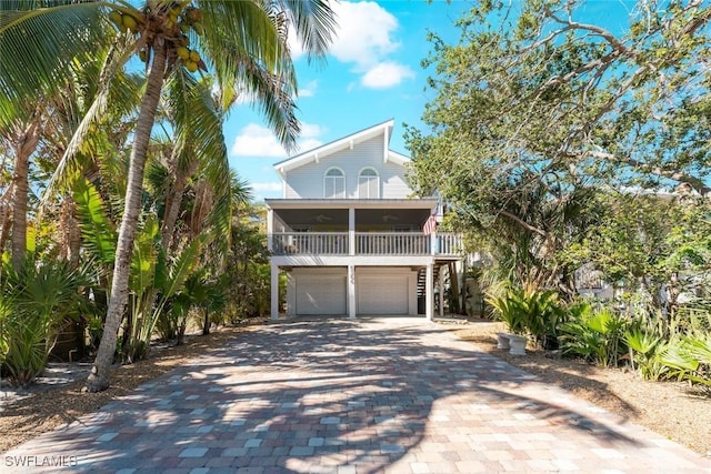 coastal home featuring a balcony, decorative driveway, and a garage