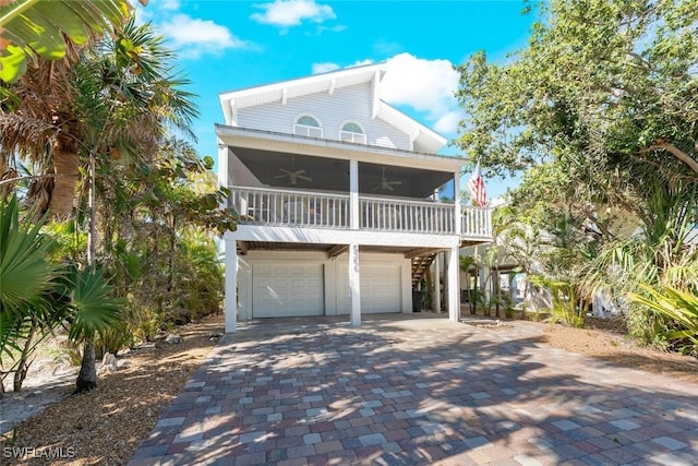 coastal home with decorative driveway, an attached garage, and ceiling fan