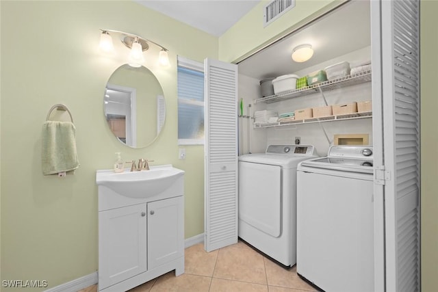 laundry area featuring a sink, washing machine and clothes dryer, laundry area, light tile patterned floors, and visible vents