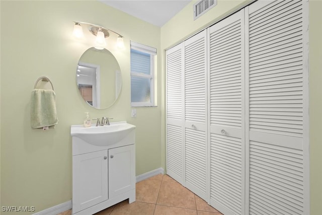 bathroom featuring tile patterned flooring, vanity, baseboards, visible vents, and a closet