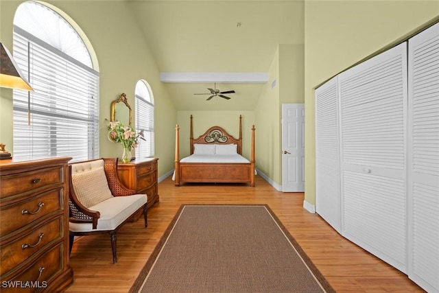 bedroom featuring light wood-style flooring, high vaulted ceiling, a closet, and baseboards