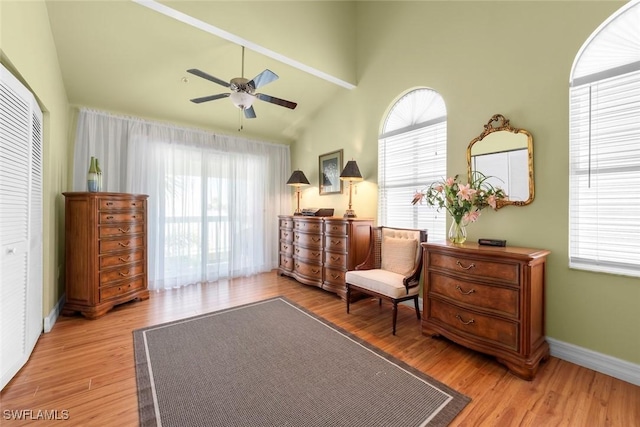 living area with a high ceiling, baseboards, light wood-style floors, and ceiling fan