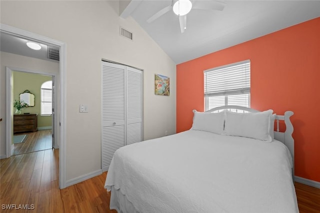 bedroom featuring visible vents, vaulted ceiling with beams, a closet, and wood finished floors
