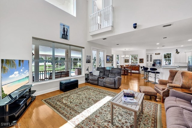 17150 Scout Camp Rd, Alva, FL 33920 - living room with visible vents, baseboards, wood finished floors, a high ceiling, and a notable chandelier