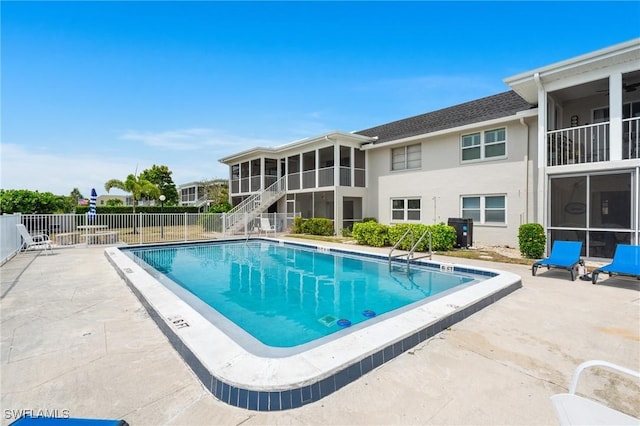 community pool with a sunroom, fence, and a patio area
