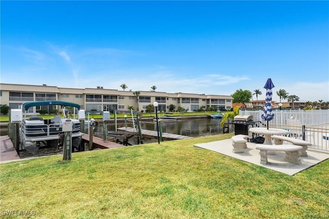 view of dock with a water view, fence, boat lift, and a yard