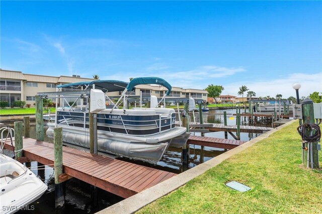 dock area featuring boat lift, a water view, and a lawn