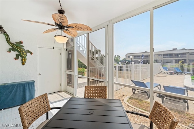 sunroom / solarium featuring outdoor dining area and a ceiling fan
