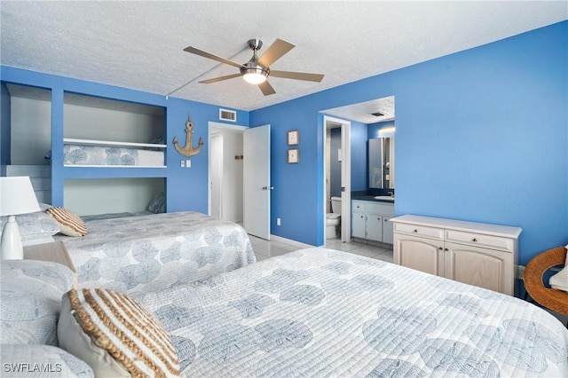 bedroom featuring a sink, visible vents, light tile patterned floors, and a textured ceiling