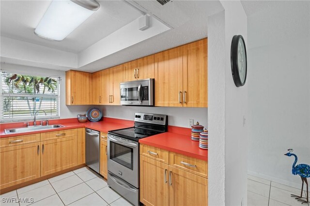 kitchen featuring a sink, stainless steel appliances, light tile patterned floors, and a raised ceiling