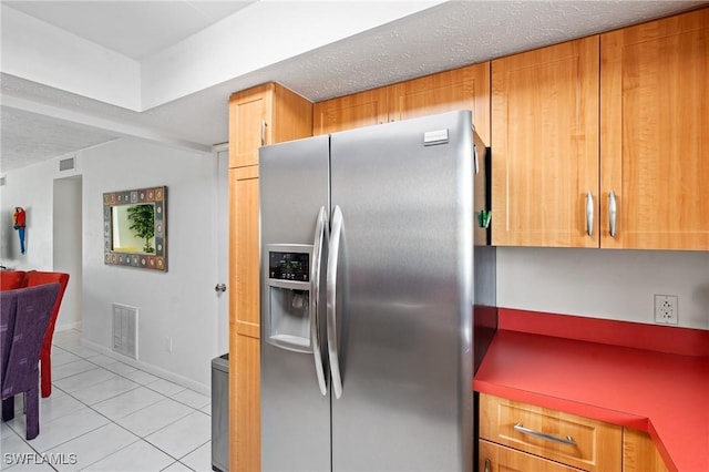 kitchen featuring a textured ceiling, visible vents, light tile patterned floors, and stainless steel refrigerator with ice dispenser