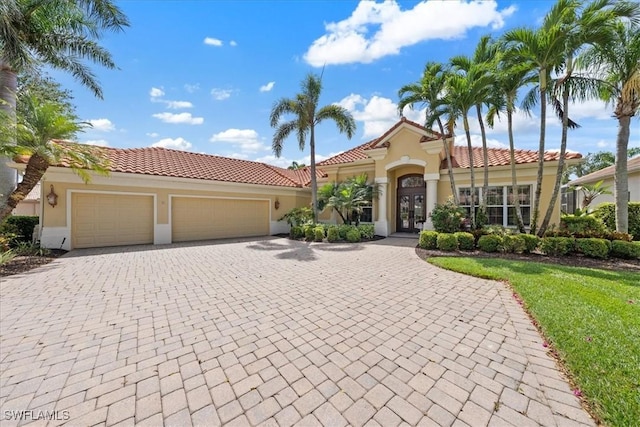 mediterranean / spanish house featuring french doors, stucco siding, decorative driveway, and a tiled roof