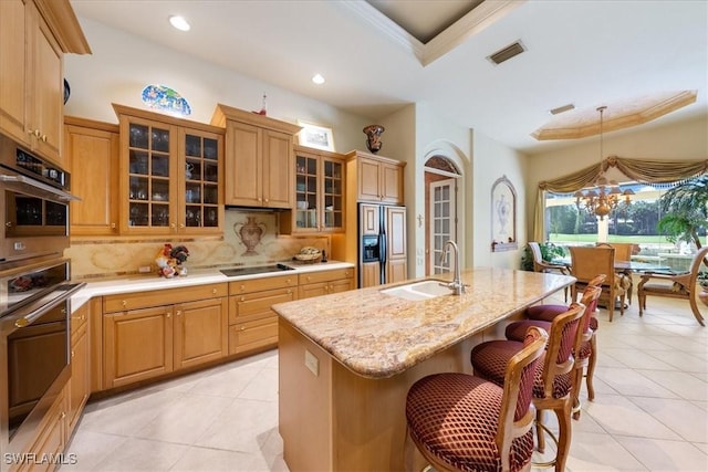 kitchen with visible vents, a sink, a kitchen breakfast bar, paneled built in refrigerator, and black electric stovetop