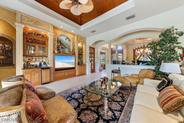 living room with visible vents, a raised ceiling, arched walkways, ceiling fan, and ornate columns