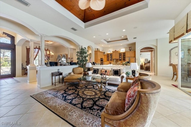 living room featuring light tile patterned floors, visible vents, ornate columns, a raised ceiling, and arched walkways