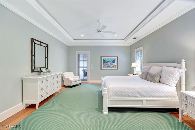 bedroom with ornamental molding, a tray ceiling, recessed lighting, and wood finished floors