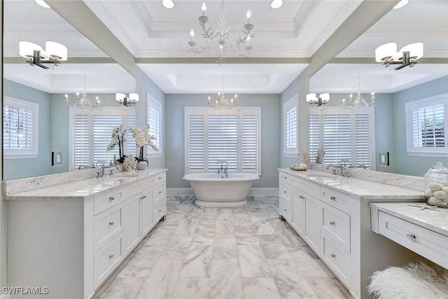 full bath featuring an inviting chandelier, a freestanding tub, and a tray ceiling