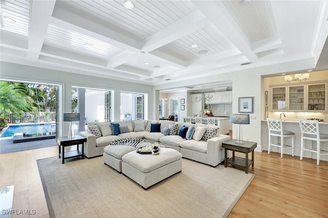 living area with an inviting chandelier, beamed ceiling, recessed lighting, light wood-style flooring, and coffered ceiling