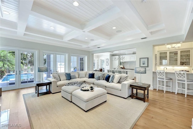 living room with french doors, coffered ceiling, beam ceiling, and a chandelier