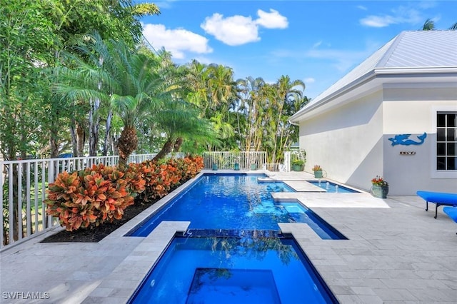 view of pool with a patio, fence, and a pool with connected hot tub